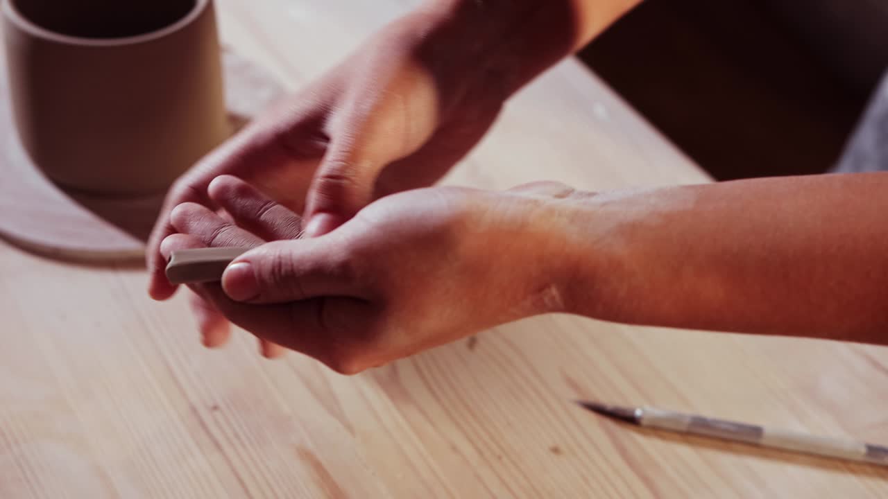 cerámica en el estudio - mujer alfarera hace un pedazo más largo de arcilla en sus manos