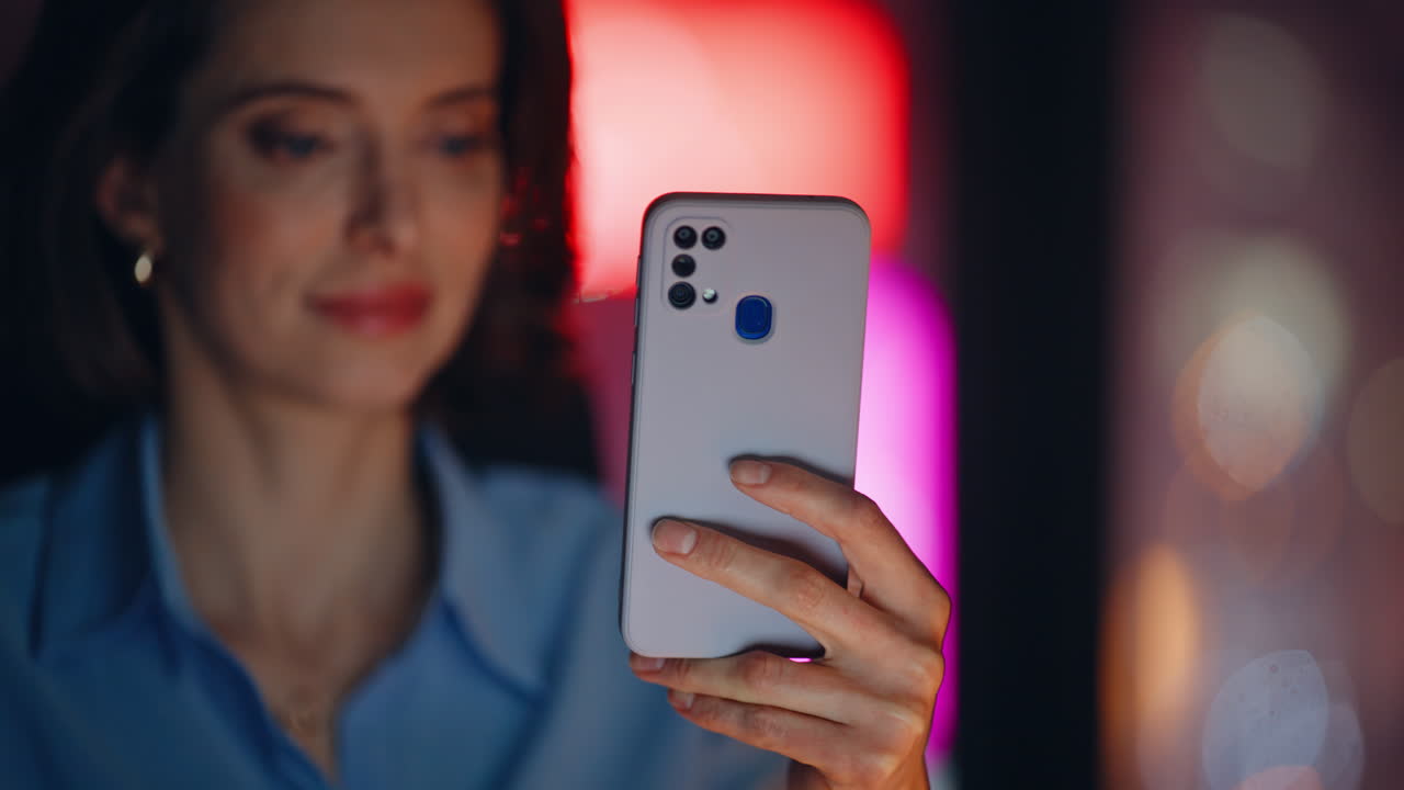 Executive browsing smartphone app at night workplace closeup. Smiling woman