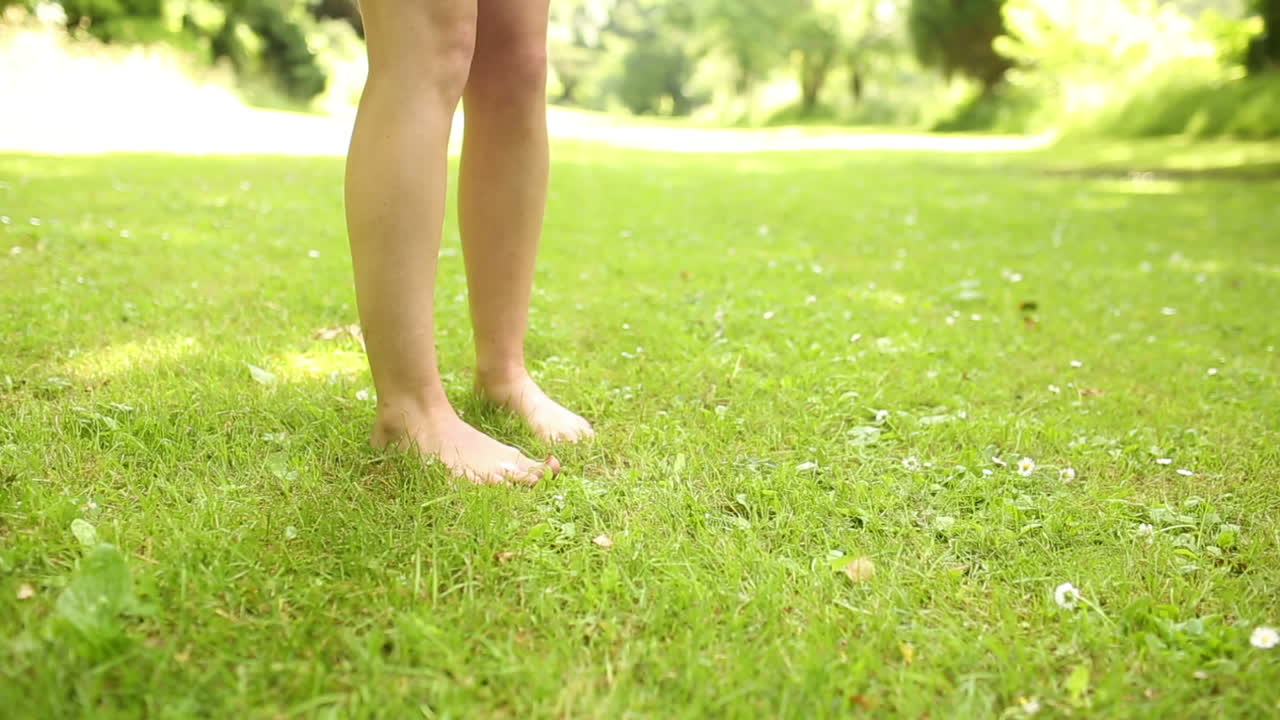 Female legs on the grass walking away
