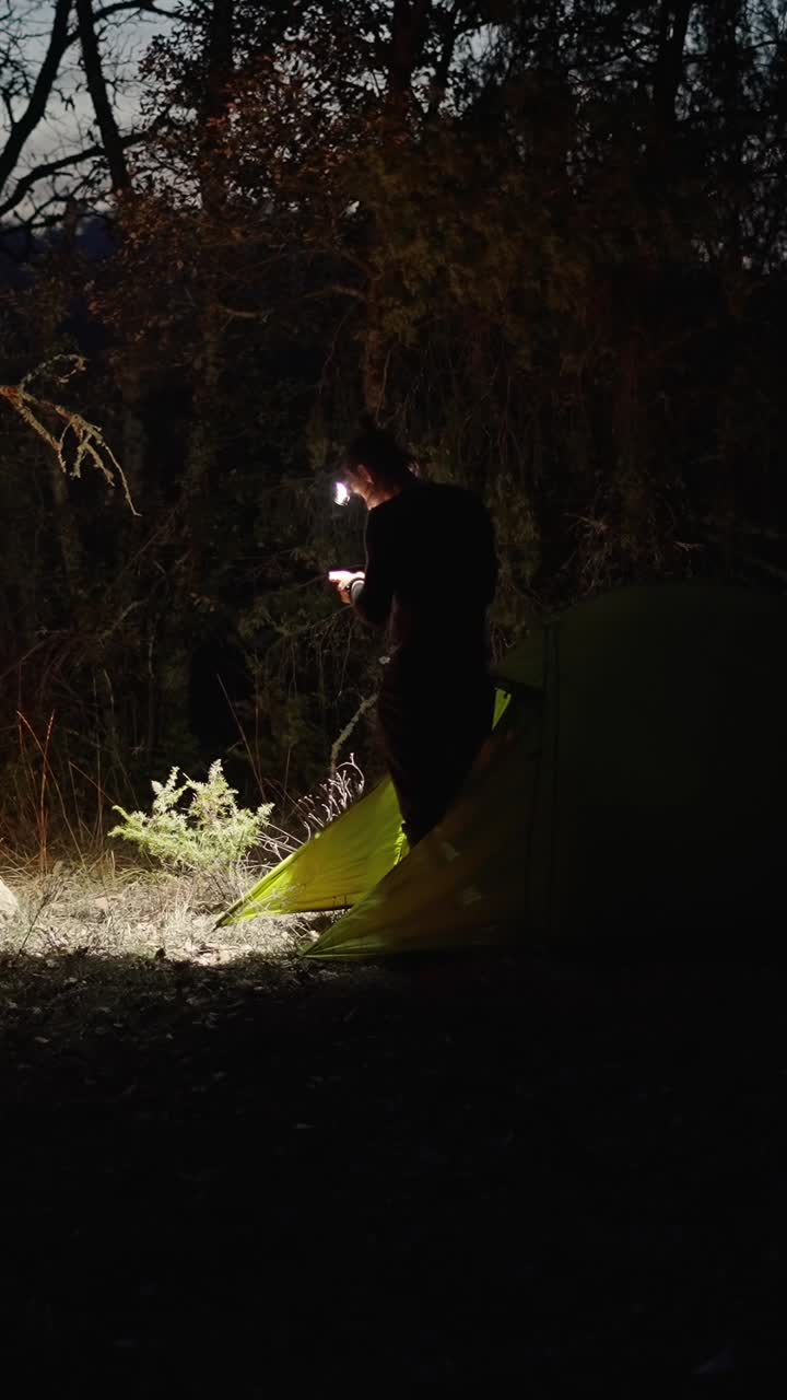 A person camping at night with a headlamp