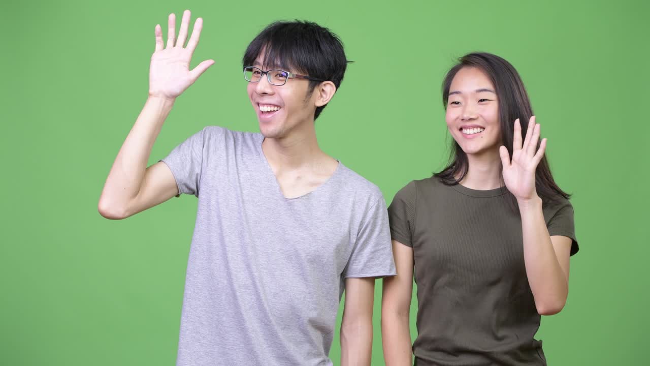 Young happy Asian couple greeting together