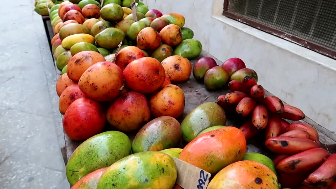 puesto callejero con frutas tropicales como mango, plátano rojo o cacao con moscas volando