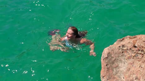 Chica-Rubia-Nadando-En-Aguas-Tranquilas-De-Color-Azul-Claro,-Haciendo-La-Braza-Y-Concentrándose-En-El-Agua,-Está-De-Vacaciones-En-El-Sur-De-España-Y-Disfruta-De-Sus-Vacaciones-Y-La-Tranquilidad-Que-Trae