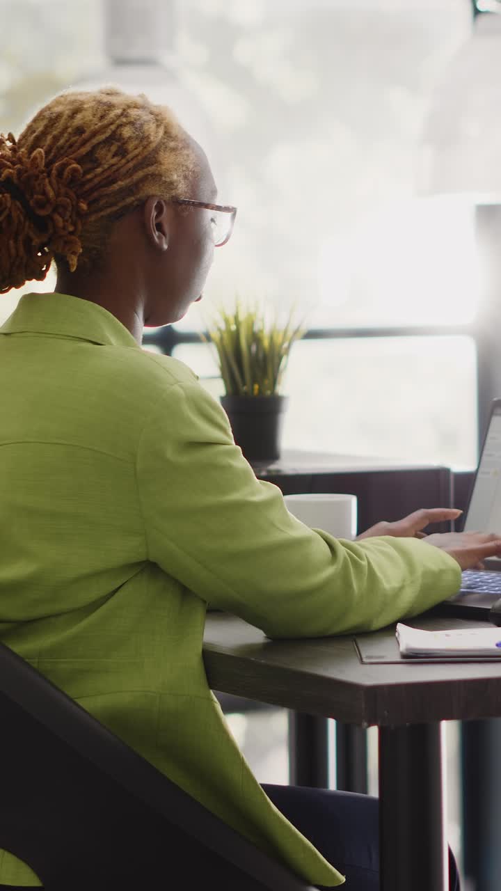 Vertical video: African american woman checking annual report on pc