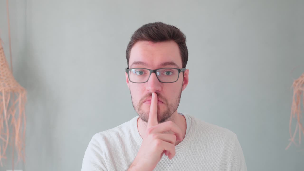 Joven con el dedo delante de la boca, señal de secreto y calma, mantén el secreto, no digas nada, no hagas ruido, guarda silencio.