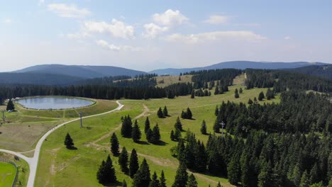 forest trails in rogla sports resort slovenia during springtime passing around a lake, aerial flyover shot