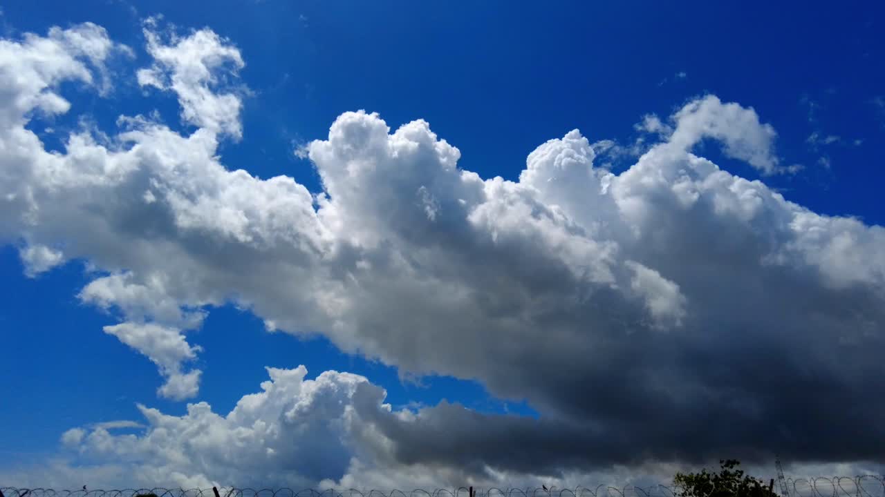 lapso de tiempo de las nubes que pasan con nube de trueno oscura en el borde con cielo azul detrás en el día de verano antes de la tormenta de verano