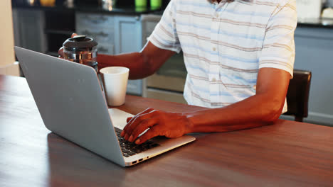 Senior man using laptop while having coffee