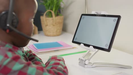 African-american-boy-sitting-at-table-and-having-video-call