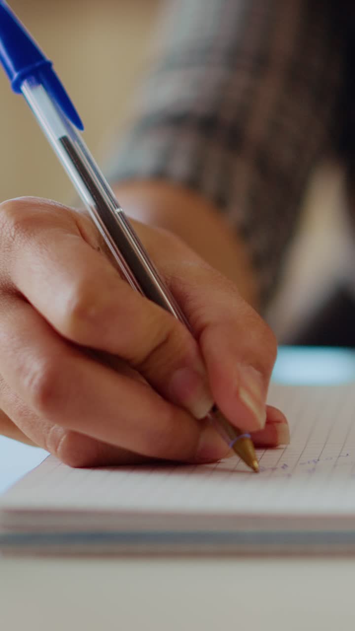 Video verticale. Lavoratore remoto scrive informazioni su carta con una penna, primo piano