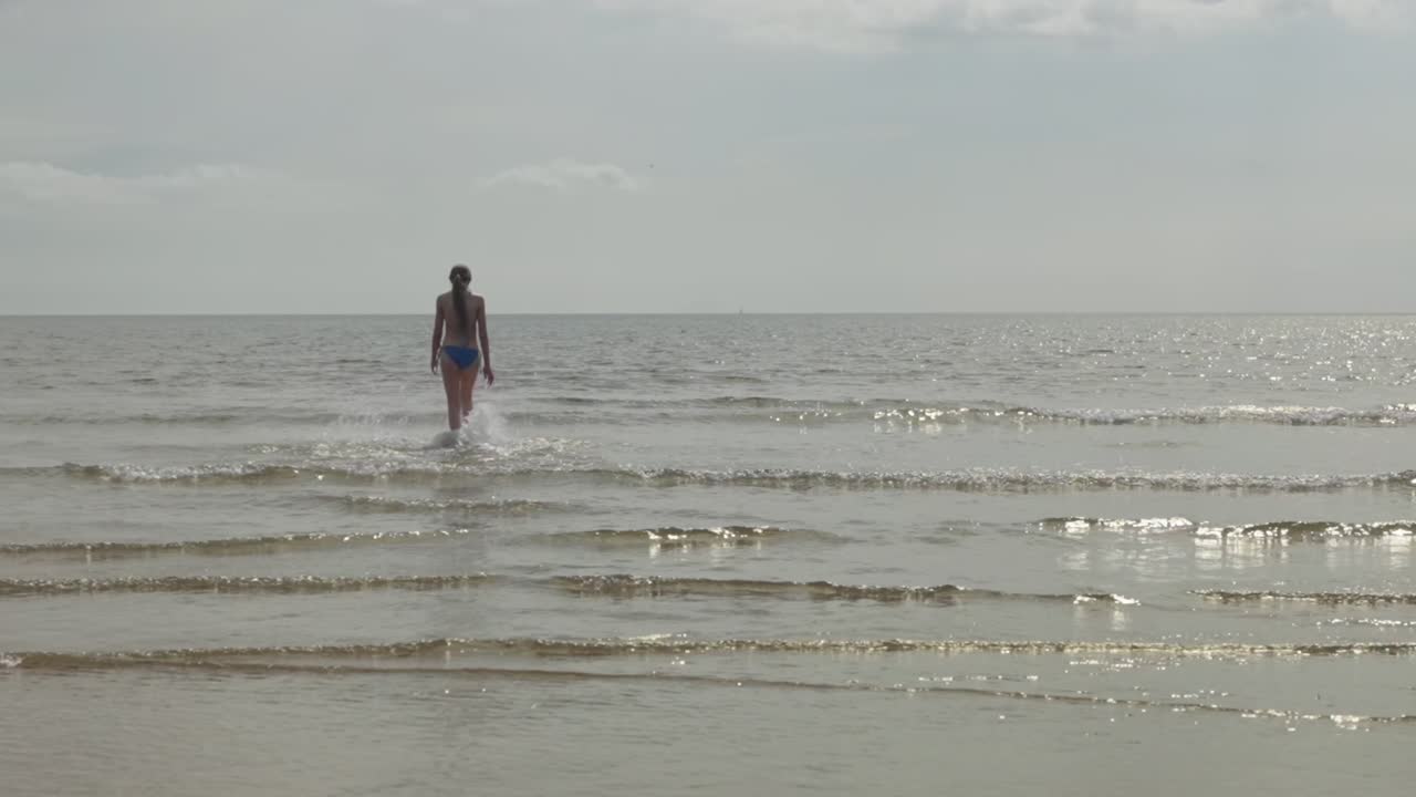 들어오는 조류에 맞서 걸어가는 느린 동영상, 십대 소녀, 해가 뜨는 장면