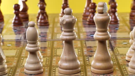 close up ,dolly shot showing wooden chess figures during starting game,yellow background