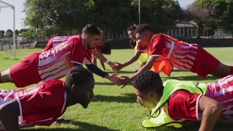 video of diverse group of male football players warming up on field,doing push-ups