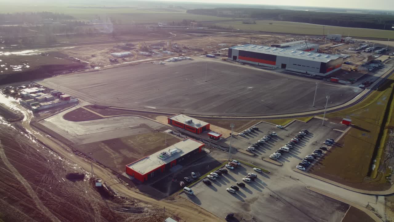 vuelo aéreo sobre un nuevo sitio de desarrollo de construcciones proyectos de almacenes y maquinaria pesada y trabajadores de la construcción están trabajando en el área.