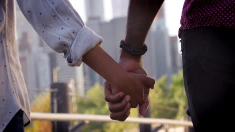 vista trasera de cerca de una pareja que se toman de la mano mientras miran el horizonte de manhattan - tomada en cámara lenta