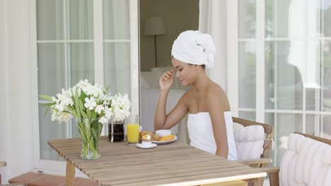 gorgeous woman wrapped in towel sitting at table