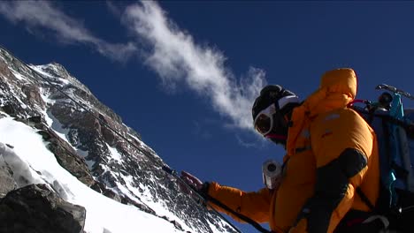 Climber-slowly-ascending-rocks-summit-in-back