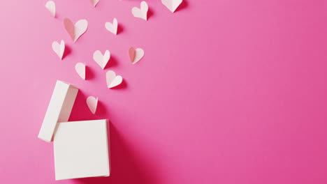 video de caja de regalo blanca abierta y formas de corazón de papel blanco, en fondo rosa con espacio para copiar