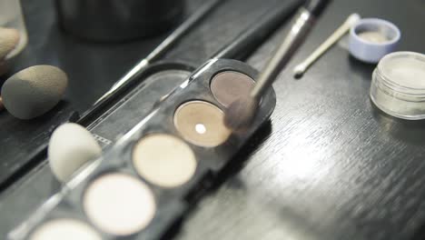 focus moving from box with eyeshadows of different colours to the close up view of makeup artist applying eyeshadow on eyelid