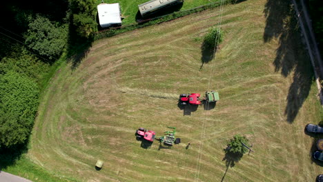 aerial view looking down at pair of tractors harvesting agricultural grassland field