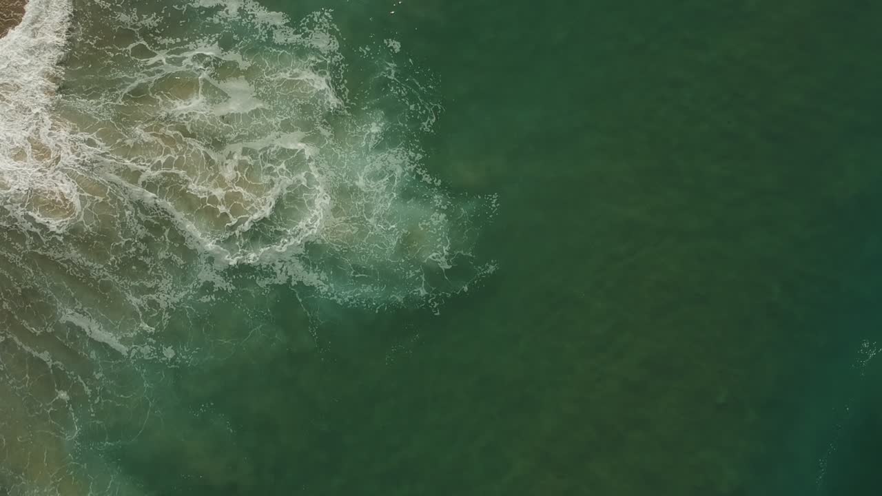 la cámara de la tarde baja la vista del dron desde el agua y las olas de la playa redonda, california