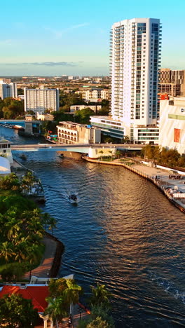 motor boats are on the narrow river in the city downtown. beautiful view of sunny miami panorama, florida, usa. vertical video