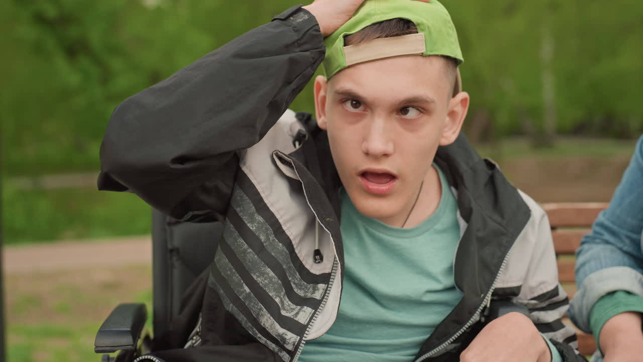 Man In Wheelchair Shows Shock Then Happiness, Young Man On Bench Experiences Surprise Transforming Into Joy, Closeup Of Young Man In Wheelchair Displaying Shock Followed By Genuine Smile