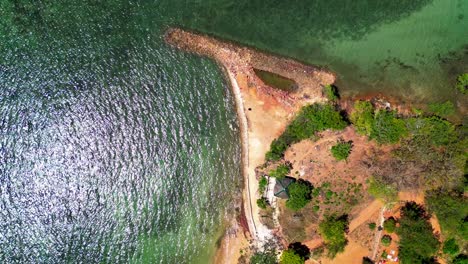 aerial view of a tropical beach with green water and lush coastline