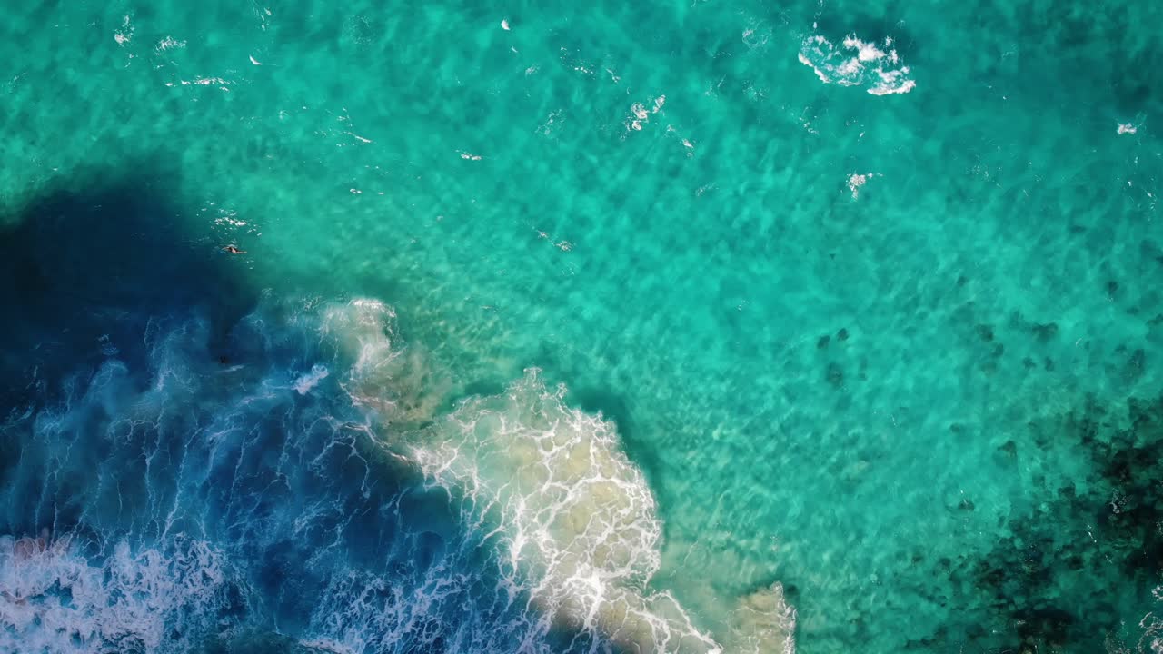 A birds eye angle from a drone of the coastline off Oahu, Hawaii. The water is very very blue.