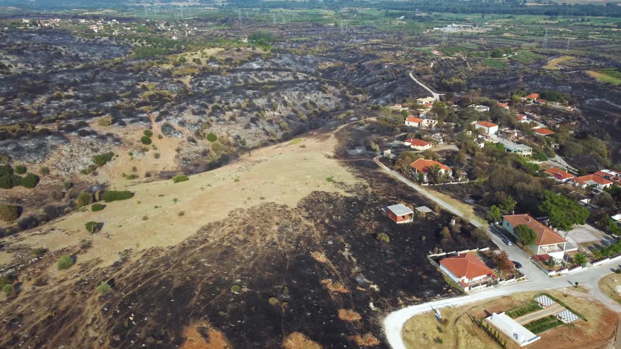foto aérea de una aldea rodeada de tierra quemada tras un incendio forestal en el norte de grecia, agosto de 2023