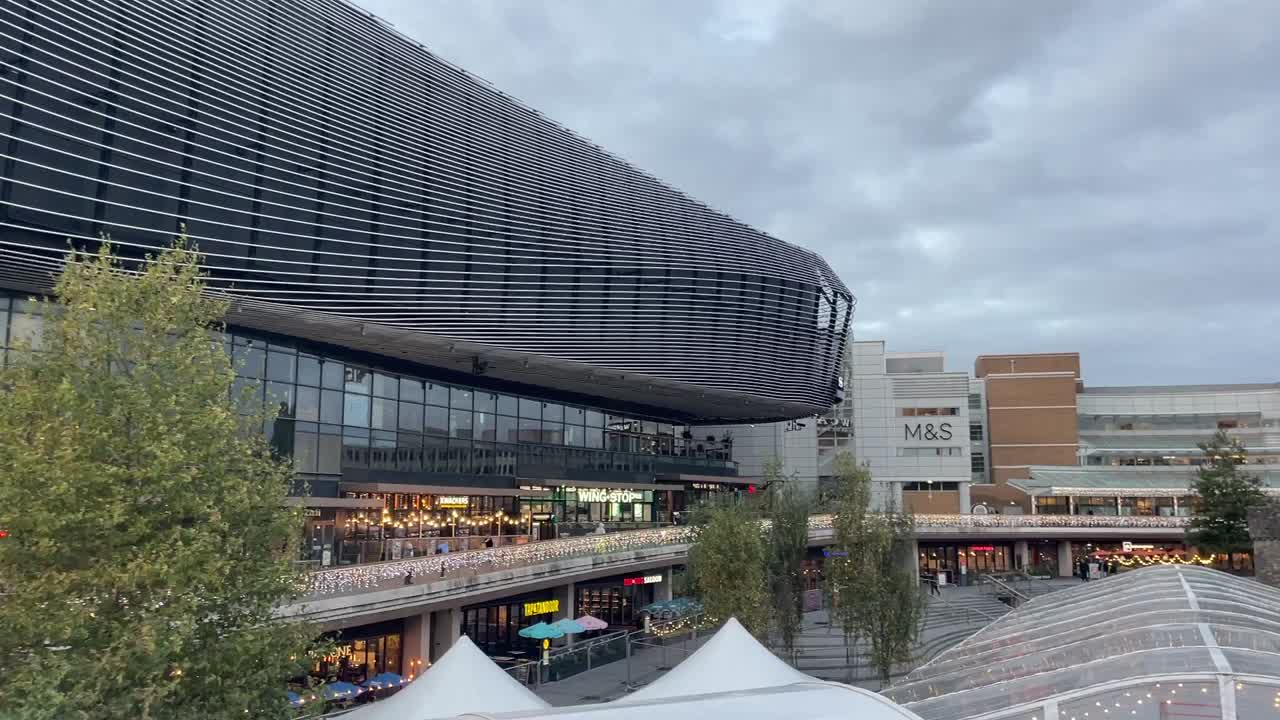 Modern architectural building at sunset in Southampton City. West Quay shopping complex with a glass facade and unique wavy design.