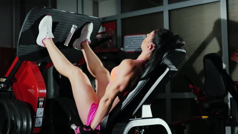 athletic woman trains muscles of the legs in the gym