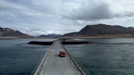 coche rojo circulando por un puente en forma de espada en islandia