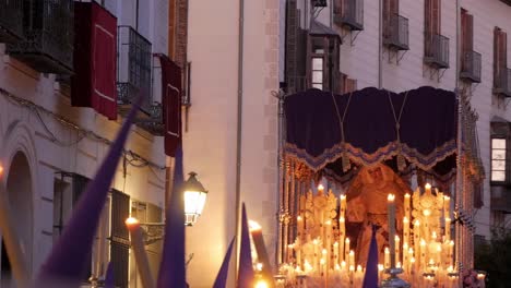 a shot capturing a "paso" float adorned with burning candles following during easter celebrations in madrid at dusk