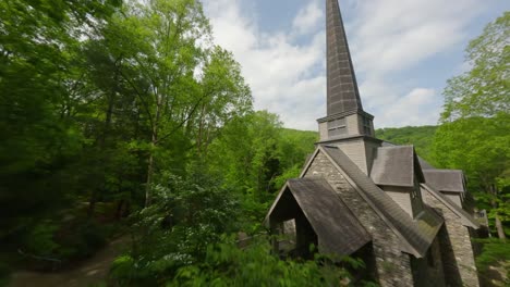 cinewhoop fpv drone footage flying through a forest until it reaches a beautiful church with a steeple