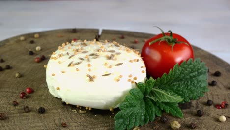 piece of fresh mozzarella, tomato and multi colored peppercorns rotate slowly on turntable.