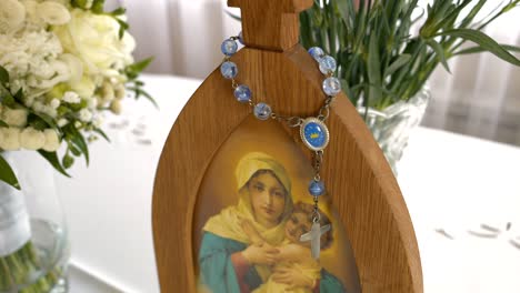 a blue rosary hanging on a wooden stand with an image of the virgin mary