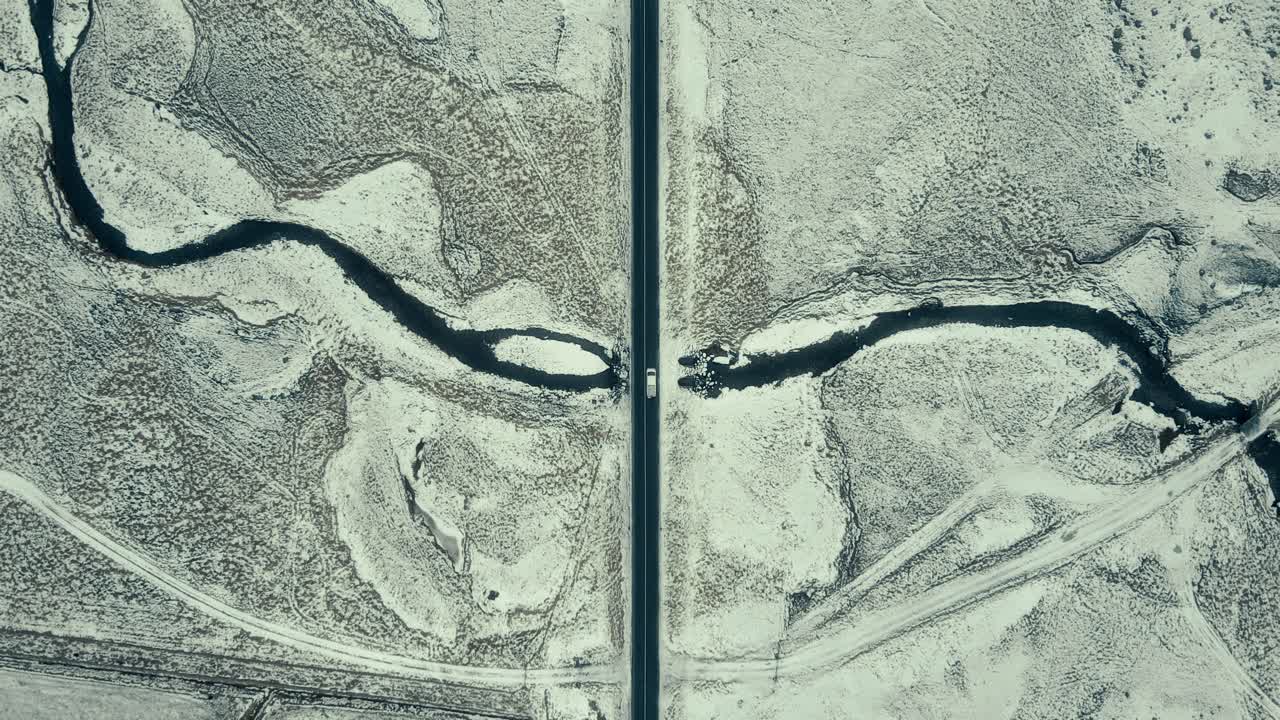 Aerial View of Car Driving on Road Through Snowy Winter Landscape with River