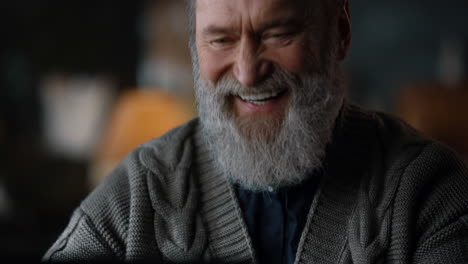 retrato de un anciano feliz riendo durante el trabajo en la computadora en el interior del hogar