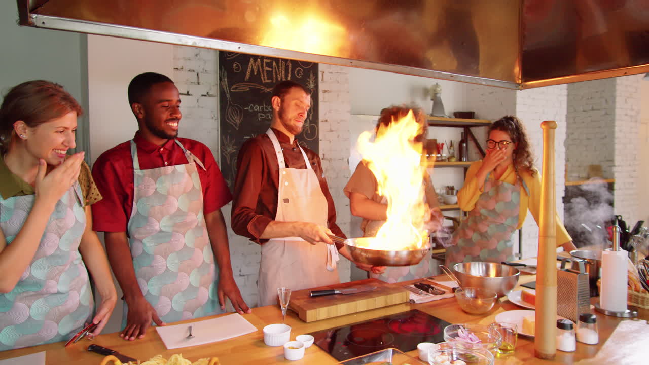 chef enseñando a los estudiantes cómo flamear la comida durante la clase de cocina