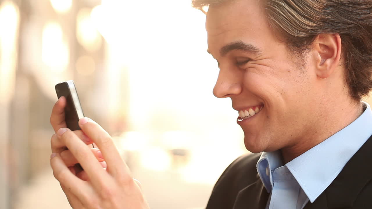 사업가 가 야외 에서 문자 메시지 를 보내고 있는 휴대 전화