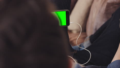 cool guy watching green-screen video on sofa at home using smart phone