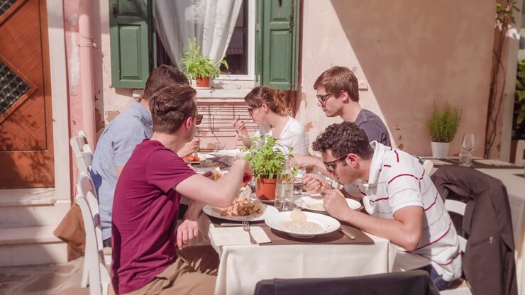 grupo de amigos disfrutando del almuerzo en un café al aire libre en italia