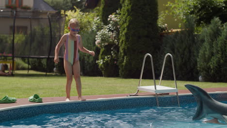 a young girl jumps into a swimming pool