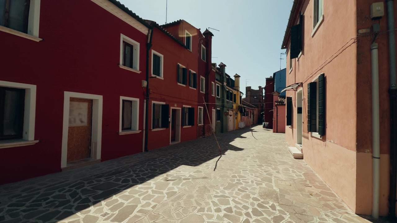 Via di Burano costeggiata da case colorate e illuminata dal sole