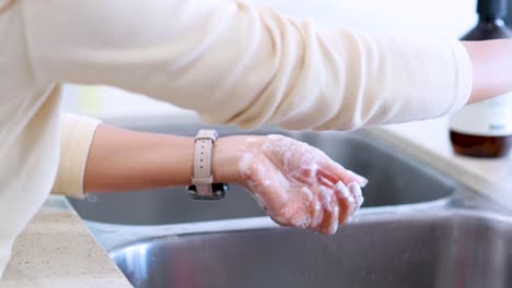 a person washes hands with soap at a modern kitchen sink, demonstrating proper hygiene technique under bright, natural lighting with close-up camera angles