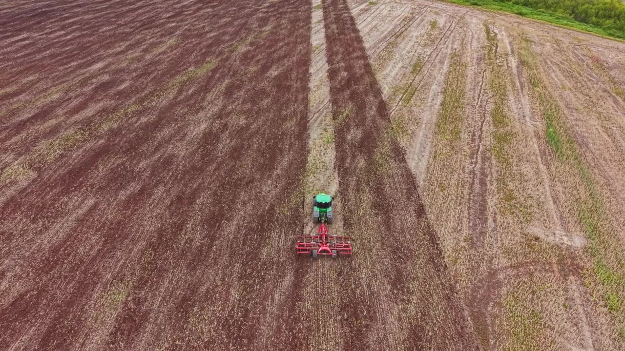 Trattore che lavora su un grande campo agricolo in campagna durante il giorno.