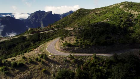 Toma-De-Drones-De-Una-Pintoresca-Carretera-De-Montaña,-Nubes-Bajas-En-Un-Día-Soleado.