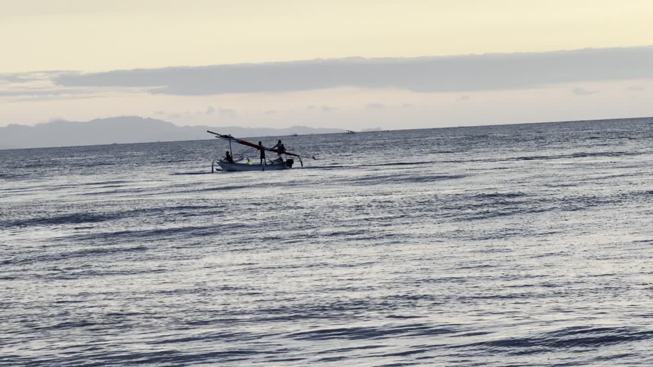 Canoa tradizionale a bilanciere con persone che attraversano un oceano calmo