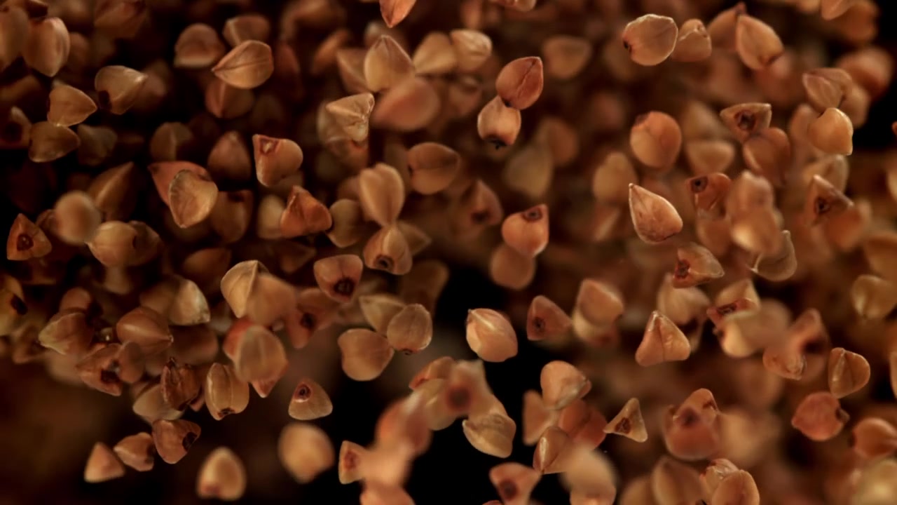 Buckwheat Grains Falling in Slow Motion Against a Black Background
